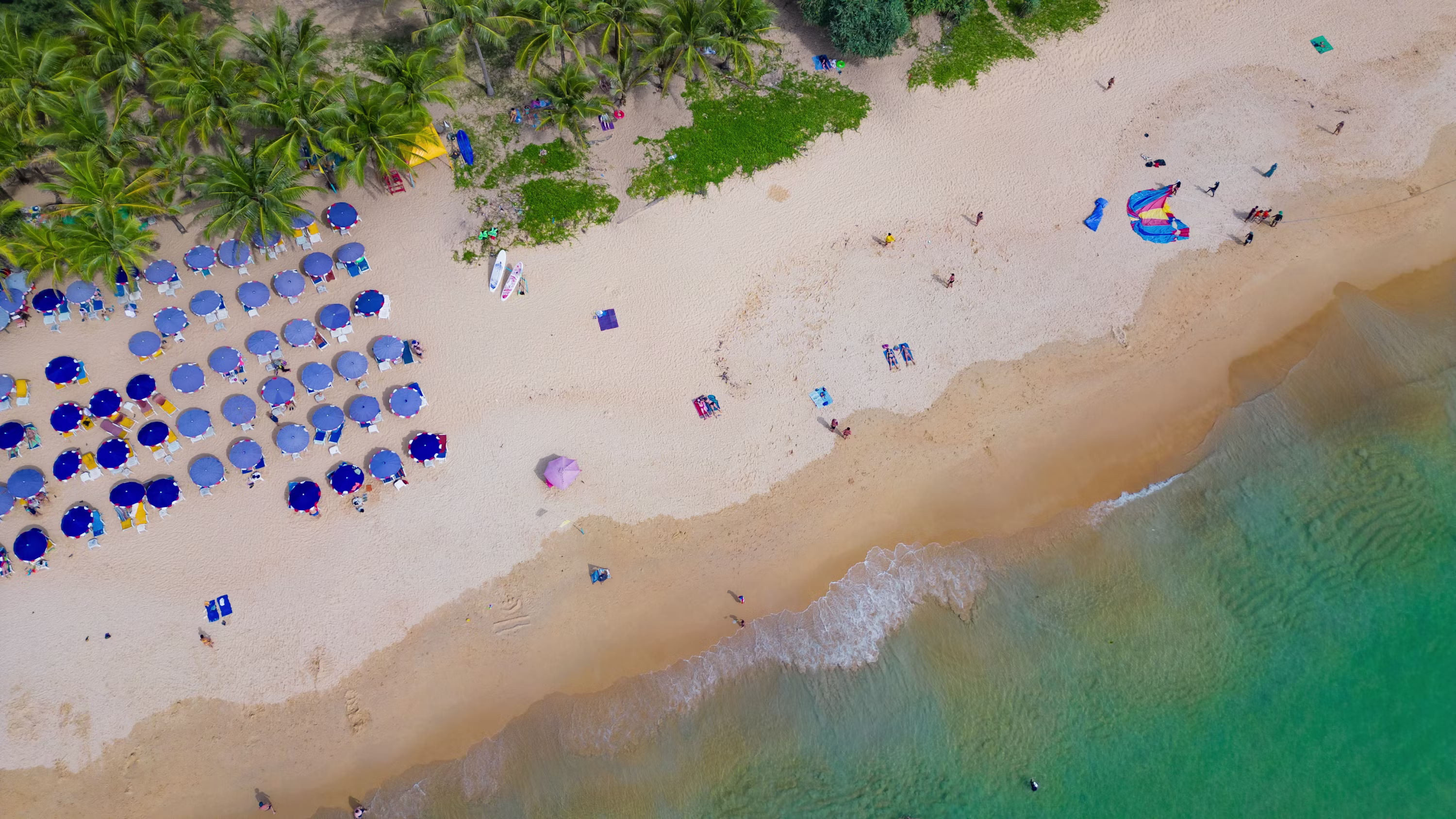 Aerial view of Nai Harn Beach in Phuket with umbrellas and turquoise water