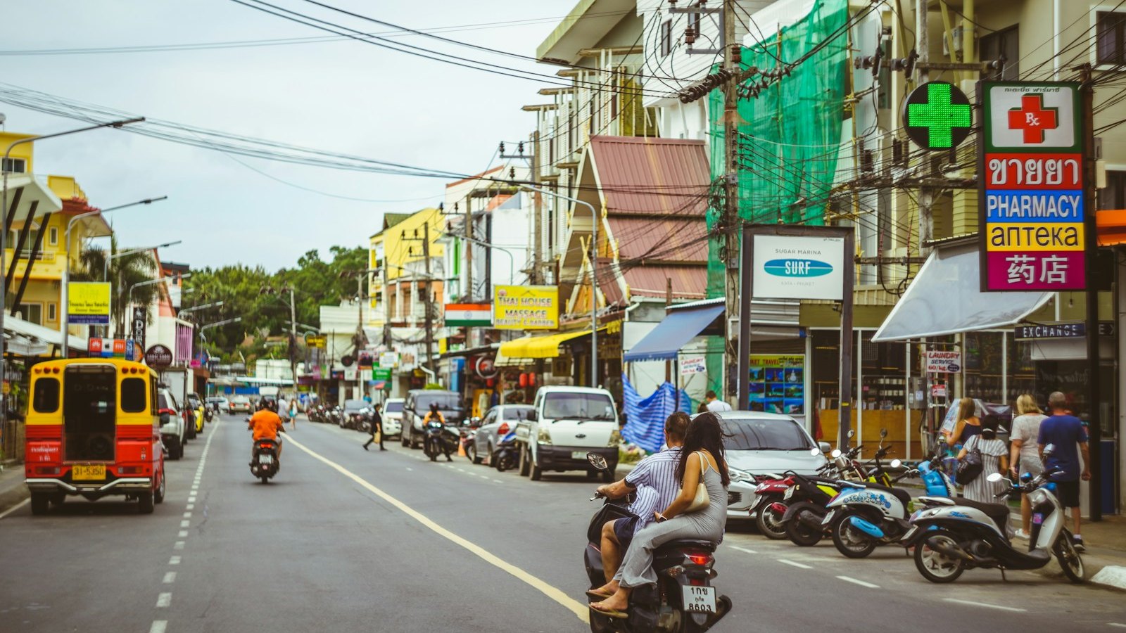 Scooters passing a pharmacy on a street in Phuket, Thailand